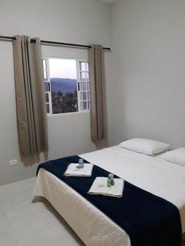 a bedroom with two beds with towels and a window at Pousada TOP in Mairiporã