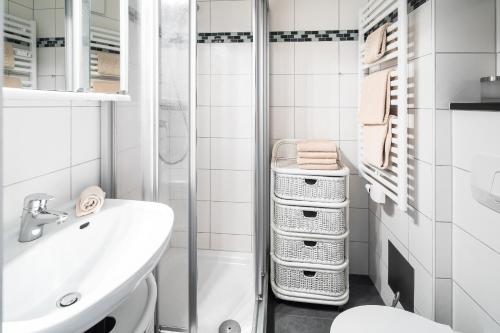 uma casa de banho branca com um lavatório e um chuveiro em Haus Iderhoff Appartment 28 em Norderney