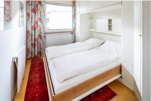 um pequeno quarto com uma cama e uma janela em Haus Iderhoff Appartment 28 em Norderney