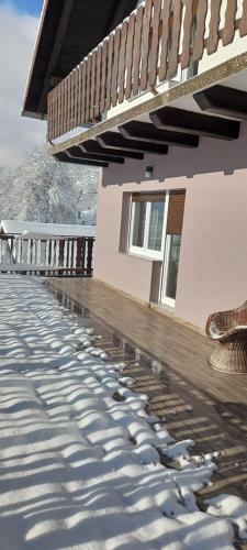 a house with a deck with snow on the ground at Apartment ROKO with sauna & view in Brod Moravice
