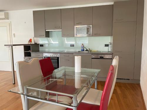 cocina con mesa de cristal y sillas rojas en City rooms, en Viena