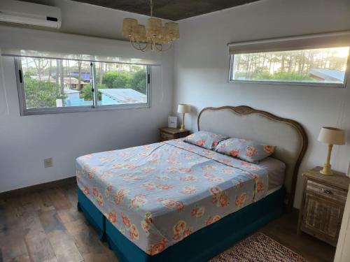 a bedroom with a bed and two windows at MarEz in Punta Del Diablo