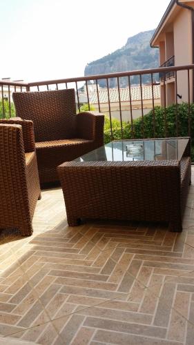 a patio with wicker chairs and a glass table at Villa Margherita in Cefalù