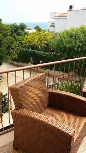 a rattan bench on a balcony with a view of the ocean at Villa Margherita in Cefalù