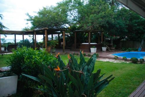um jardim com um gazebo e uma piscina em Jurerê - Direto na Praia em Florianópolis