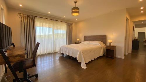 a bedroom with a bed and a desk and a piano at Hotel Boutique Las Taguas in Constitución