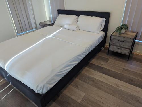 a large bed with white sheets and pillows on it at Huge Holiday Home 4Beds 2Baths in Gladstone near Shopping Center in Gladstone