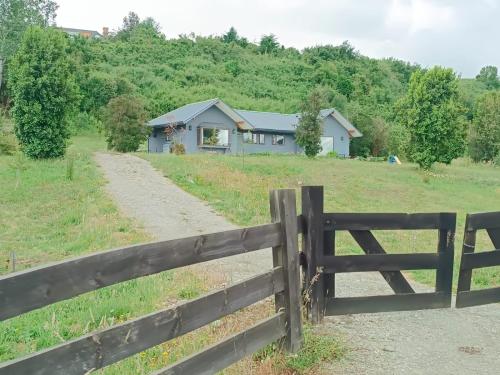 a fence in front of a field with a house at Casa con excelentes 2 habitaciones 1 Doble Matrimonial y otra 2 camas indiv con vista al volcán, Puerto Varas in Llanquihue