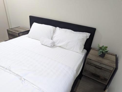 a white bed with a black headboard and white pillows at Christa's 4Bedroom Entire Private House Gladstone City in Gladstone