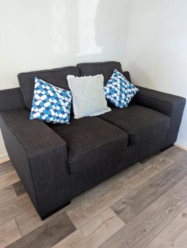 a black couch with three pillows on it at Christa's 4Bedroom Entire Private House Gladstone City in Gladstone