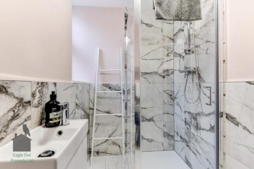a white bathroom with a shower and a sink at 1 bed flat for two close to train station with private parking by Eagle Owl Property in Worthing