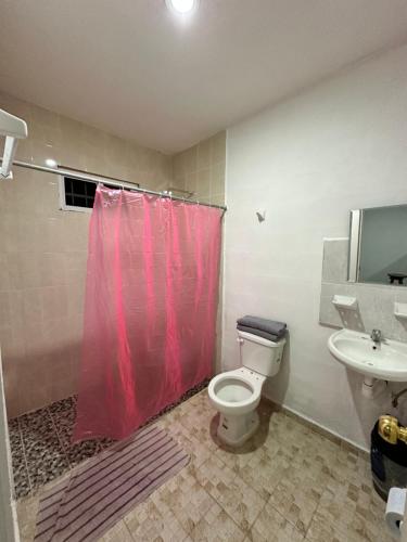 baño con cortina de ducha roja y aseo en Departamento 48 Street, en Valladolid