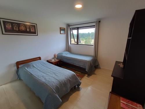 1 dormitorio con 2 camas y ventana en Casa con excelentes 2 habitaciones 1 Doble Matrimonial y otra 2 camas indiv con vista al volcán, Puerto Varas en Llanquihue