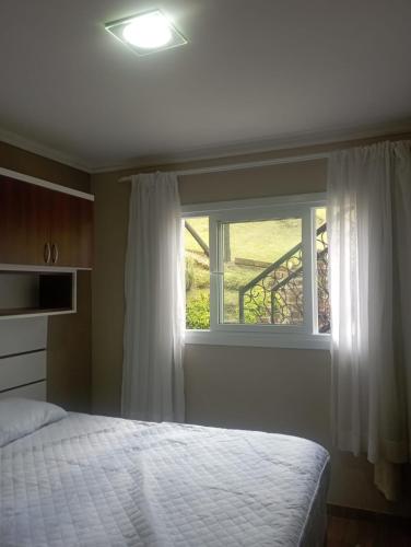 ein Schlafzimmer mit einem Bett und einem Fenster in der Unterkunft Aconchego Apartamentos da Serra in Canela