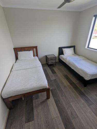 two beds in a room with wooden floors at Gladstone Entire House 4 Beds 2 Baths Air-conditioned in City in Beecher
