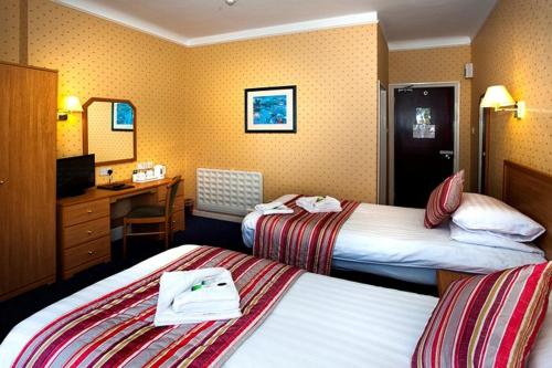 a hotel room with two beds and a desk at Devon Towers Hotel in Bournemouth