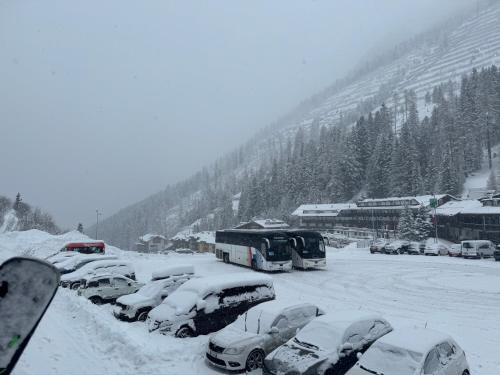 a parking lot covered in snow with buses and cars at Ski Lodge Pampeago in Tesero