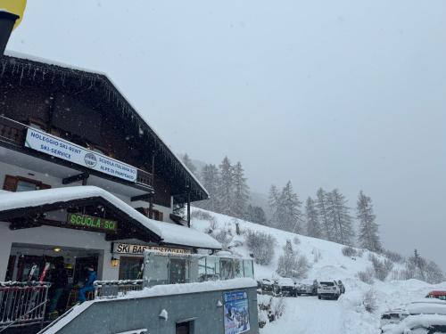 a snow covered mountain with cars parked in front of a building at Ski Lodge Pampeago in Tesero