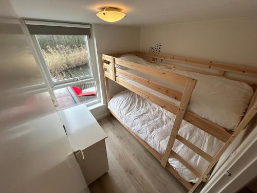 Lakeside Cottage De Rijd في Nieuwe-Niedorp: سرير بطابقين في غرفة صغيرة مع نافذة