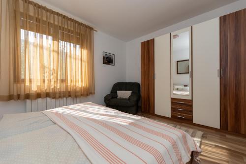 a bedroom with a bed and a chair and a window at Apartmani Rumora Gorski kotar in Tuk Vojni