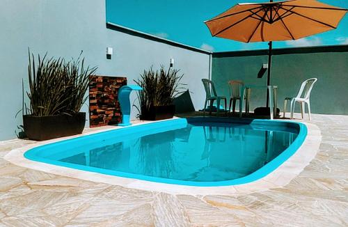 a swimming pool with an umbrella and a table and chairs at Sobrado em Piçarras com piscina in Piçarras
