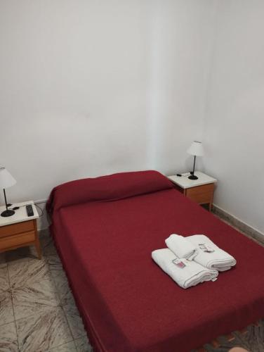 a bedroom with a red bed with two white towels on it at Hotel Parque in Necochea