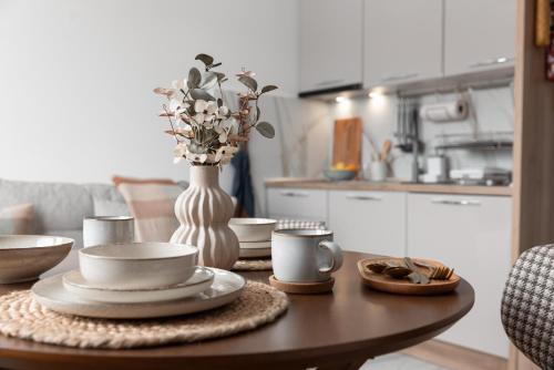a table with plates and cups and a vase with flowers at Glečer Kop, Apartment A14, FREE Parking Garage in Kopaonik