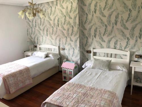 sypialnia z 2 łóżkami i ścianą z tapetą w obiekcie LA BUGANVILLA w mieście Gijón