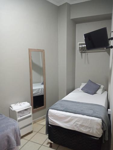 a bedroom with a bed and a mirror and a television at Hotel Apiacas in Ribeirão Preto