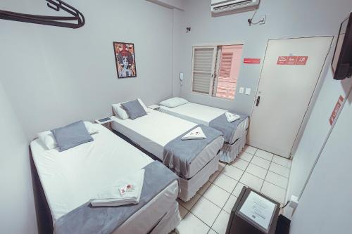 a room with two beds and a window at Hotel Apiacas in Ribeirão Preto