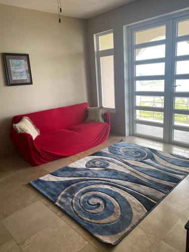 a living room with a red couch and a carpet at Top of the Hill Blue Sunshine in Long Swamp