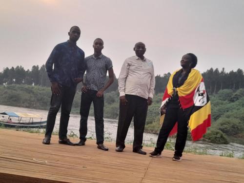 a group of four people standing on a pier with a flag at Jusvero Motel in Jinja