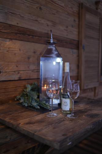 two wine glasses and a bottle on a wooden table at Bergchalet Four Seasons in Reit im Winkl