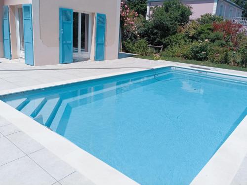 une grande piscine bleue à côté d'une maison dans l'établissement B&B avec piscine proche de Paris, à Maisons-Laffitte
