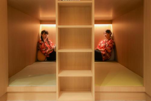 two people sitting inside of a closet with shelves at Castle Inn Sendai in Sendai