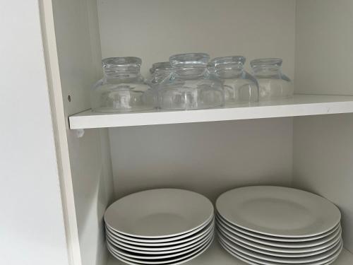 a white shelf with glass jars and plates on it at Vista Bahia in Bahia Inglesa