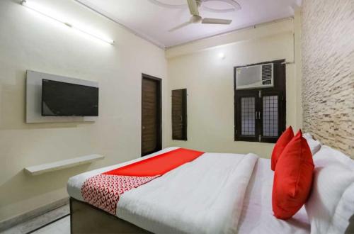 een slaapkamer met een bed met rode kussens en een televisie bij OYO Hotel sweet Elite in Meerut