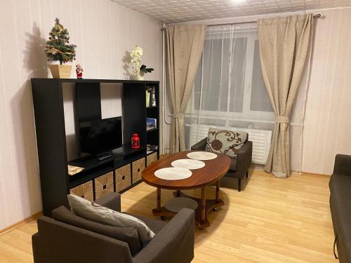 een woonkamer met een tafel en een televisie bij Cozy Center Apartment in Druskininkai in Druskininkai
