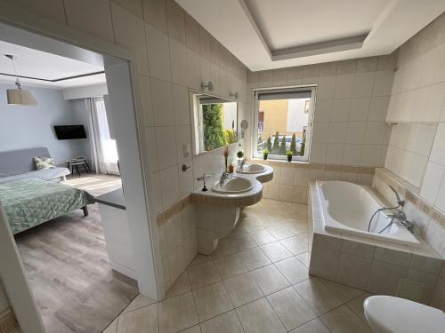 a bathroom with two sinks and a tub and a bed at WiLLA APART in Władysławowo