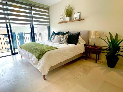 a bedroom with a bed with pillows and a plant at Viva Nautica Solaria 2 BR condo with sea view, 2 pools, hot tub in Cabo San Lucas