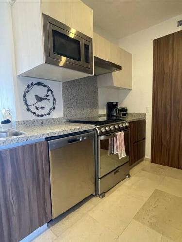 a kitchen with a stove and a microwave at Viva Nautica Solaria 2 BR condo with sea view, 2 pools, hot tub in Cabo San Lucas