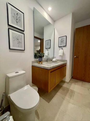 a bathroom with a toilet and a sink and a mirror at Viva Nautica Solaria 2 BR condo with sea view, 2 pools, hot tub in Cabo San Lucas