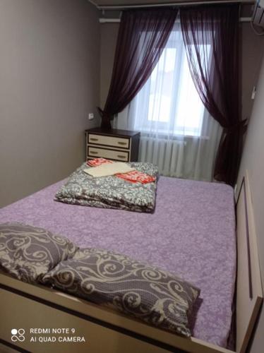 a bedroom with a bed with purple sheets and a window at Автовокзал Apartaments 2kv in Dnipro