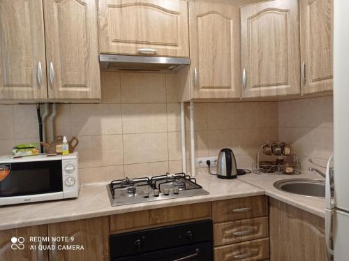 a kitchen with a stove and a microwave at Автовокзал Apartaments 2kv in Dnipro