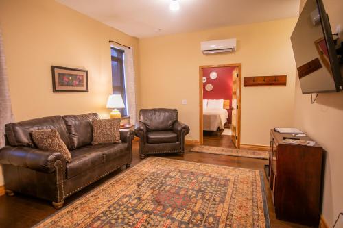 a living room with leather furniture and a television at Goldfinch Suites in Elkader