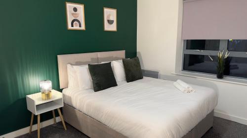 1 dormitorio con 1 cama con pared verde en Long Stay - Free Parking - Contractors - Train Station - Students en Colchester