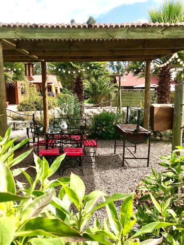 a wooden pergola with a table and benches in a garden at Departamentos y Cabañas Il Bosco in Algarrobo
