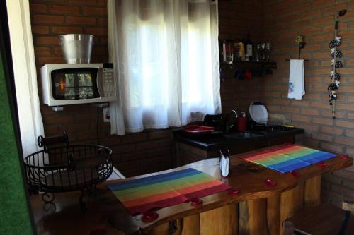 a kitchen with a wooden table and a microwave at Chalés de Analuz in Visconde De Maua