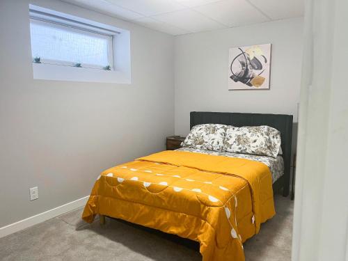 a bedroom with a bed with a yellow blanket at Stylish Basement Suite with Modern Comforts in Winnipeg