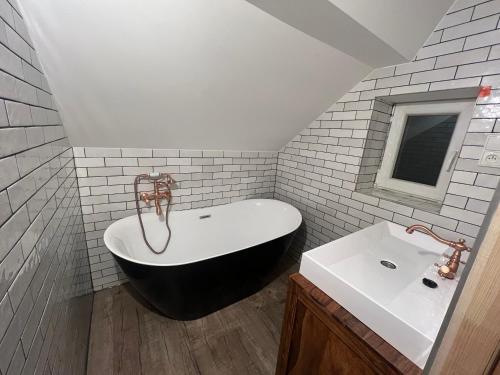 La salle de bains est pourvue d'une baignoire en noir et blanc et d'un lavabo. dans l'établissement Chata Porcelánka, à Desná